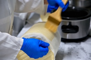 large block of cheddar being brushed