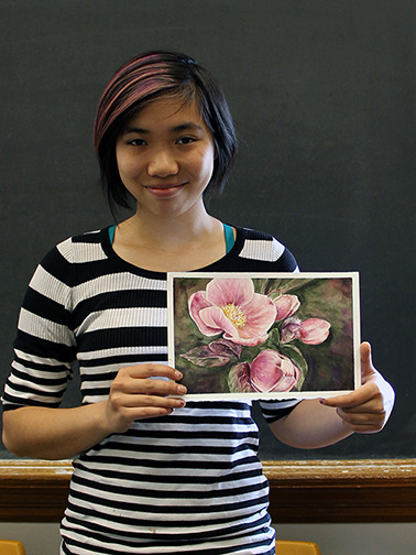 A student poses with a painting of a flower