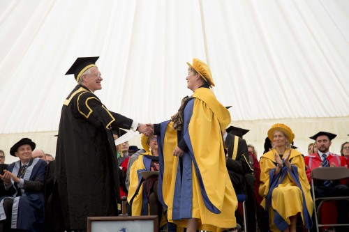 a woman shakes hands with a man at a graduation ceremony