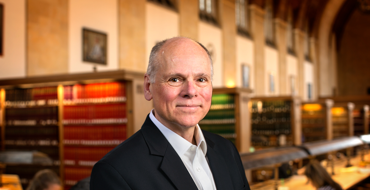 Max Pfeffer stands in a library to have his portrait taken