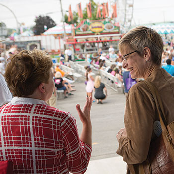 Two women stand and talk together at a state fair