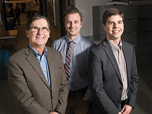 Three men in professional clothing stand together for a group photo