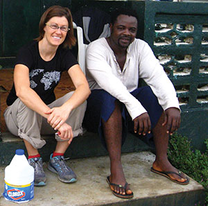 A woman and a man sit outside a house on the steps
