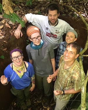 Two men and three women stand in a hole in the ground