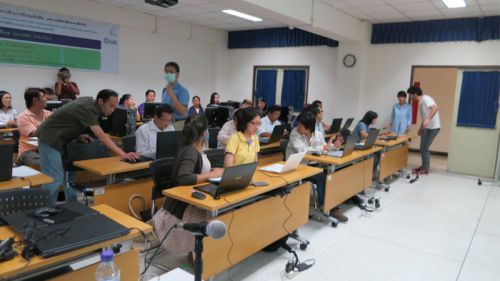 A large group of people work on their laptops in a classroom