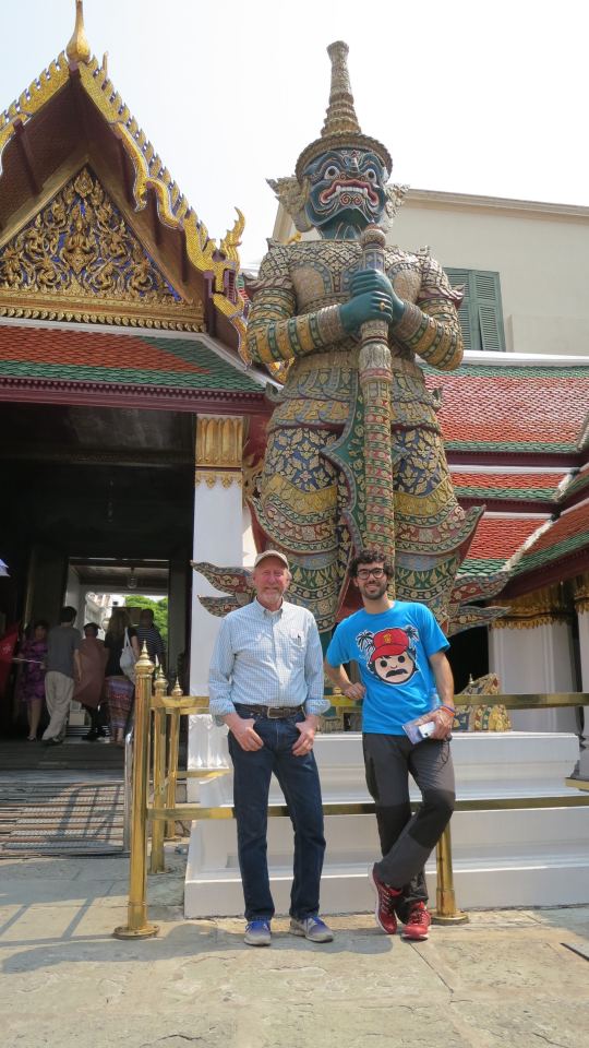 Two men stand in front of a statue in Thailand