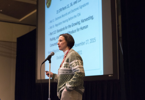 A woman stands on stage and gives a presentation