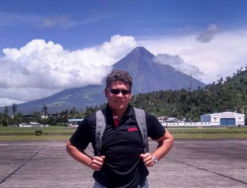 A man stands in front of a volcano in the Philippines