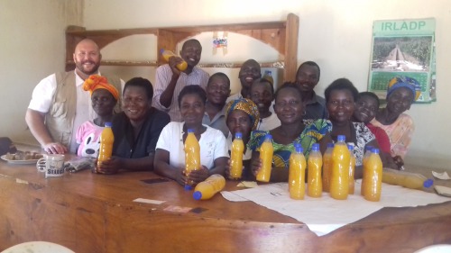 A group of people pose with bottles of juice