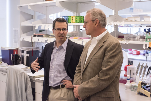 Two men stand and talk in a laboratory