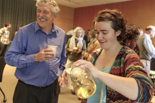 A girl pours an infusion tea into a cup while standing next to a man