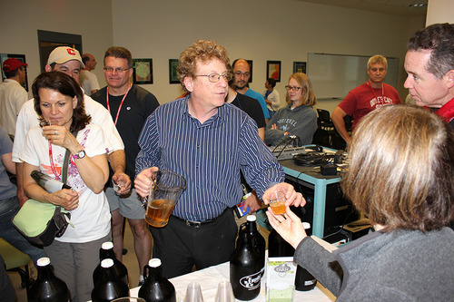 A group of people stand and drink beer from plastic cups