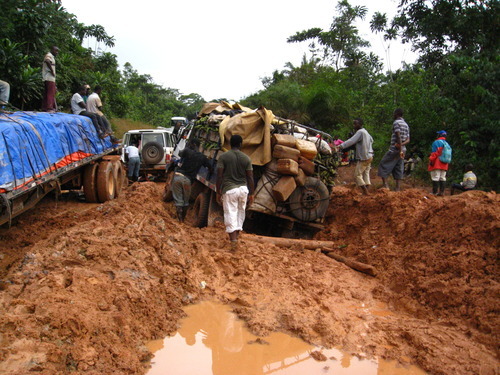 A car with lots of equipment on it gets stuck in the mud on a road in Liberia