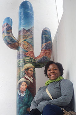 A woman stands next to a art piece shaped like a cactus in a museum