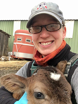 A woman smiling hugging a cow