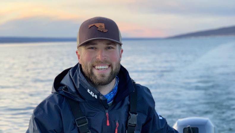 A male student smiles from a boat on the ocean