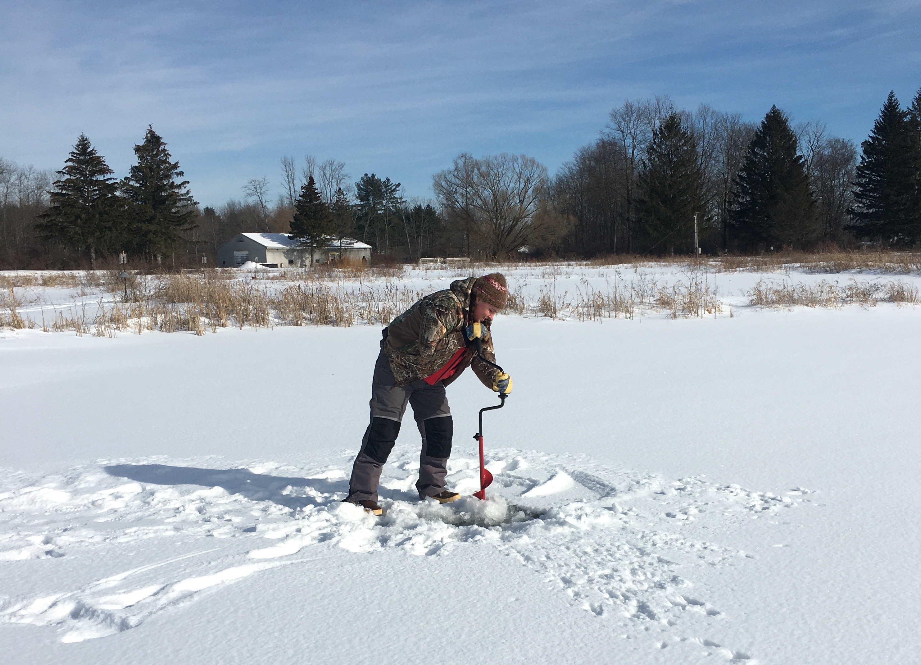 woman drilling into a frozen lake