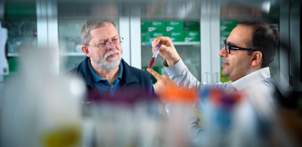 Two researchers examine a vial of beet juice