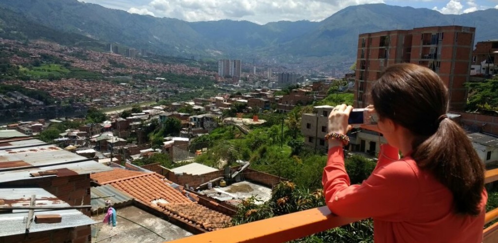 graduate student takes a photo of a city and mountains from a balcony