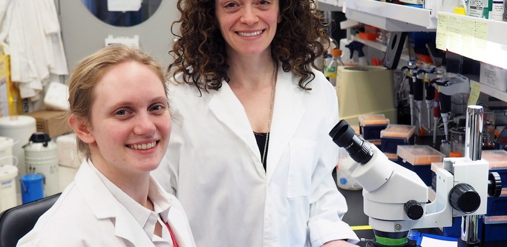 researcher and professor stand in a lab with a microscope