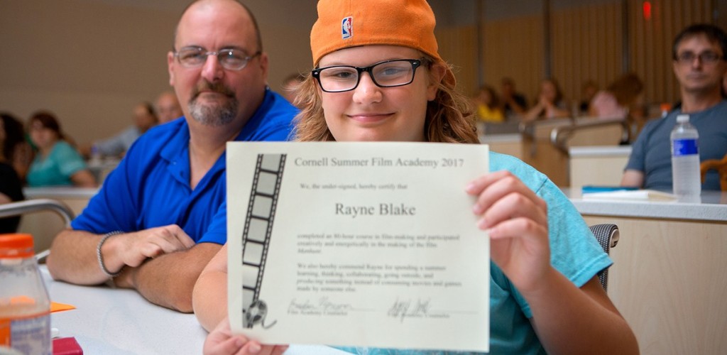 middle school student holds up certificate with father