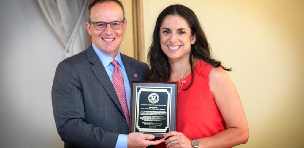 Joel Malina and Christa Glazier stand, smiling, and holding a plaque