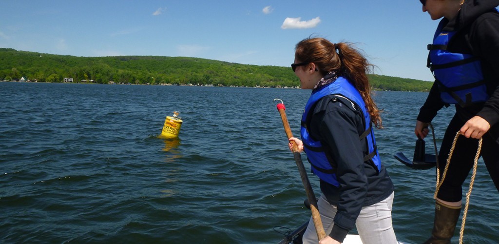 students on a boat ready to reach for a research bouy