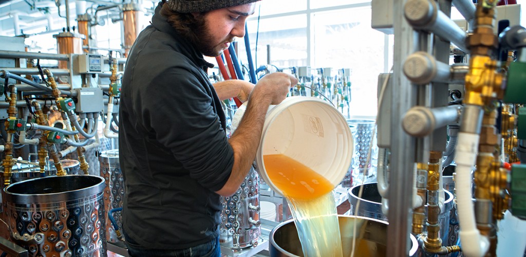 Collin Dillingham pouring apple juice into a fermentation tank