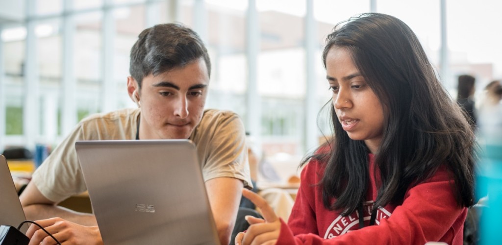 Two students collaborating at a laptop in Schurman Hall atrium