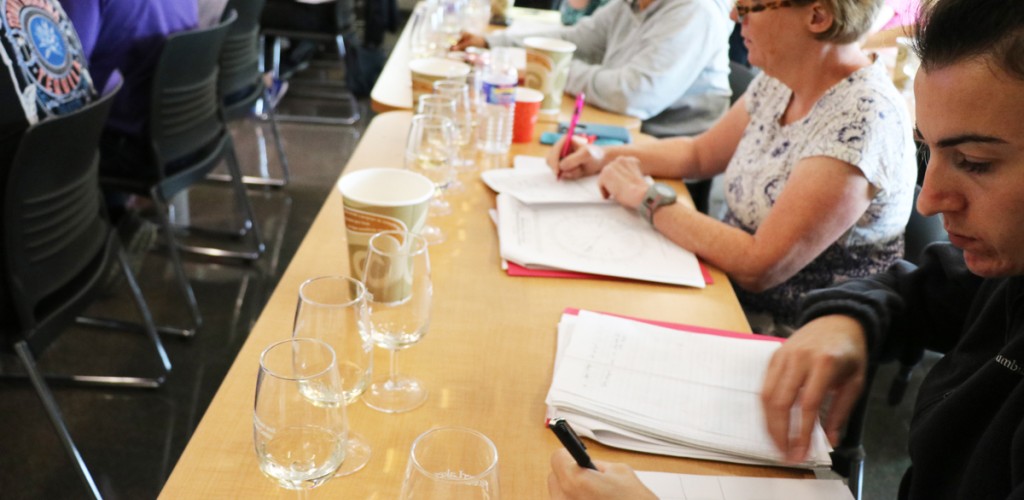 People at a table with wine glasses and reading information in front of them