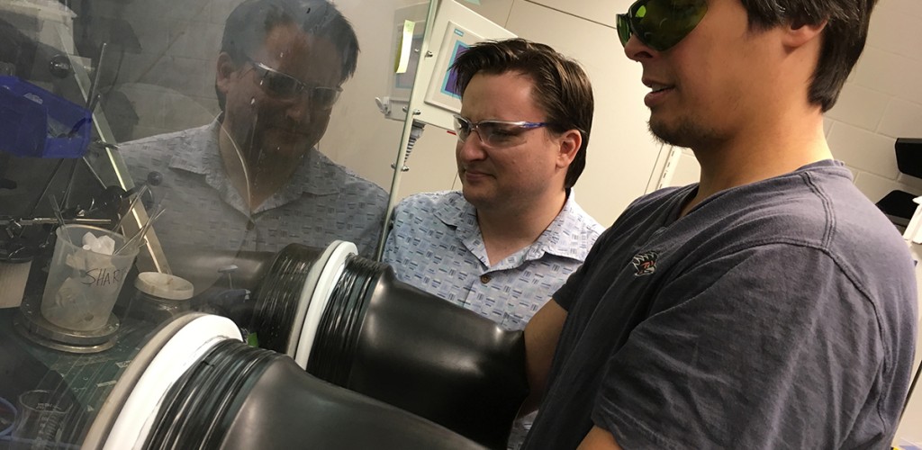 chemist has arms in safety system while other researcher looks on