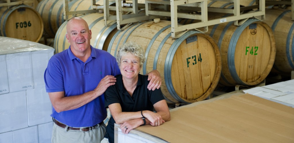 Pete and Tacie Saltonstall stand in front of wine casks