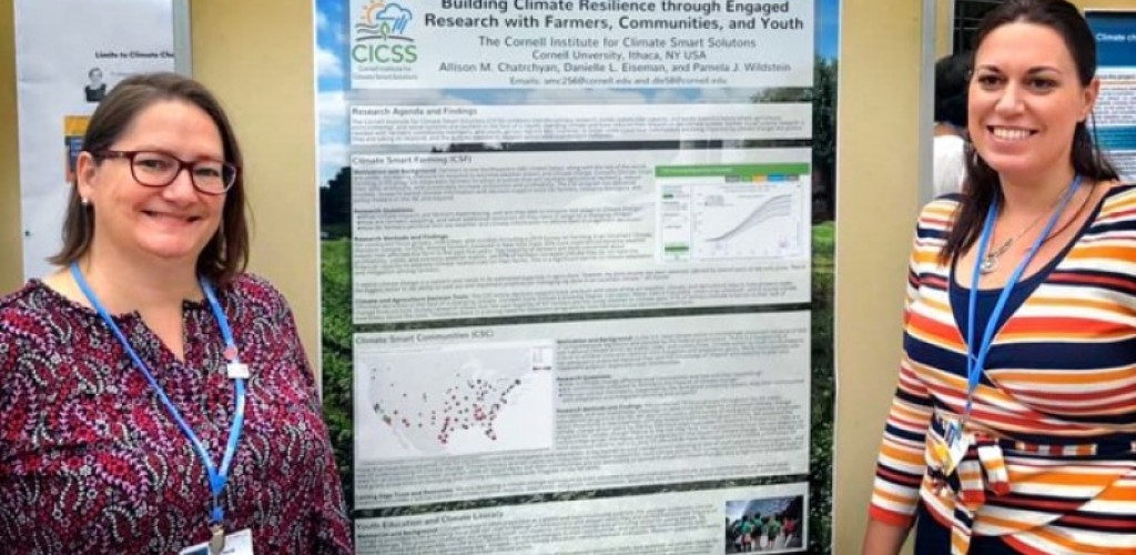 Two women stand on either side of a poster detailing climate change research