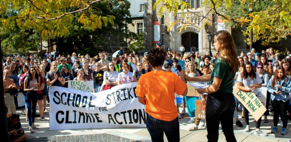 Two female students standing before and speaking to a large crowd outside on Cornell's campus