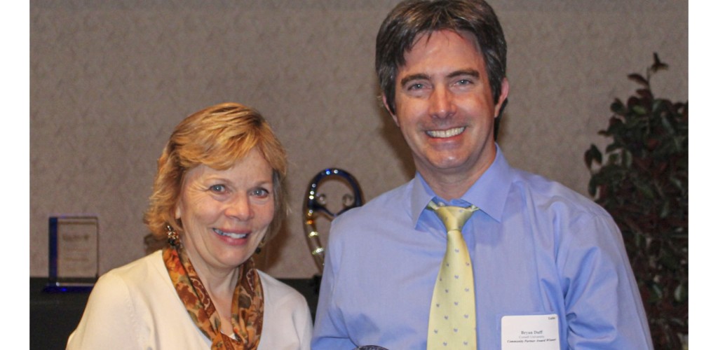 A woman stands next to a man holding an award