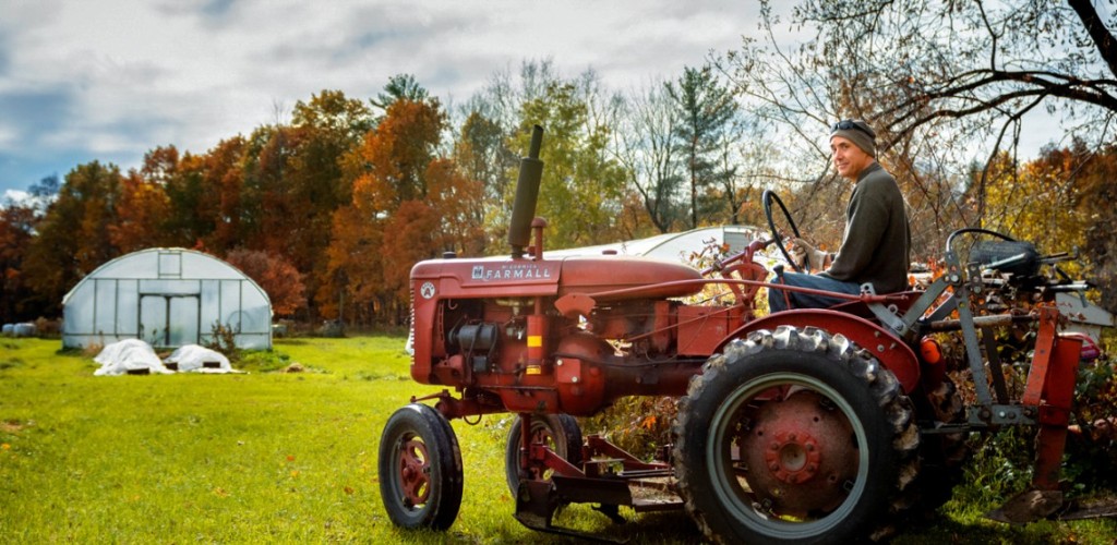 A man sitting on a red tractor outside 