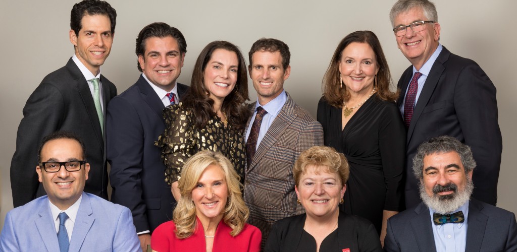 Two women and two men sit in the front row, while two women and four men stand and smile in the background of a posed picture