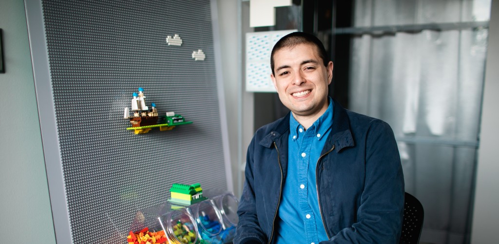 A man with short brown hair sitting in a chair in an office 