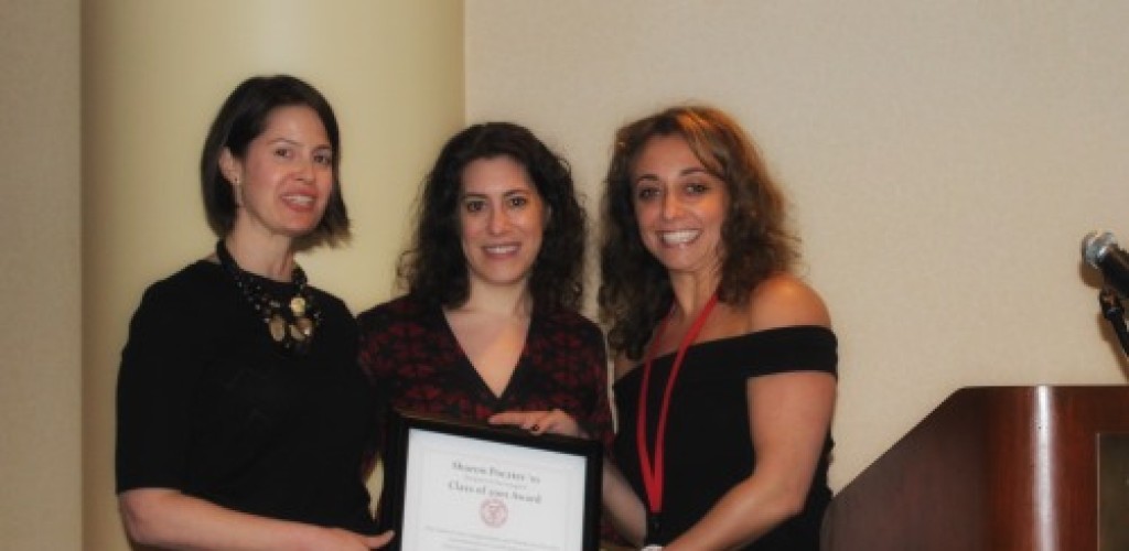 Three women stand holding a certificate