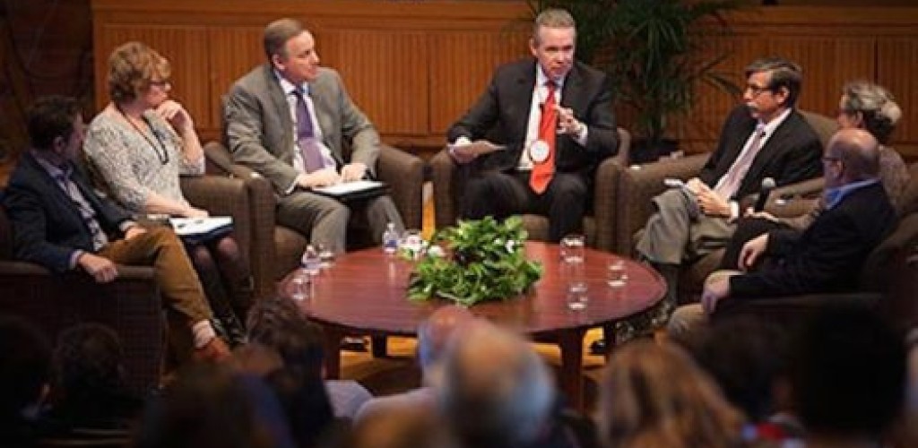 Seven people sit around a table and talk