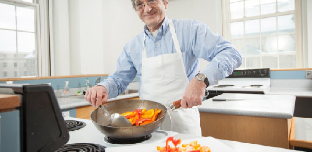 A man cooks peppers in a pan on the stove