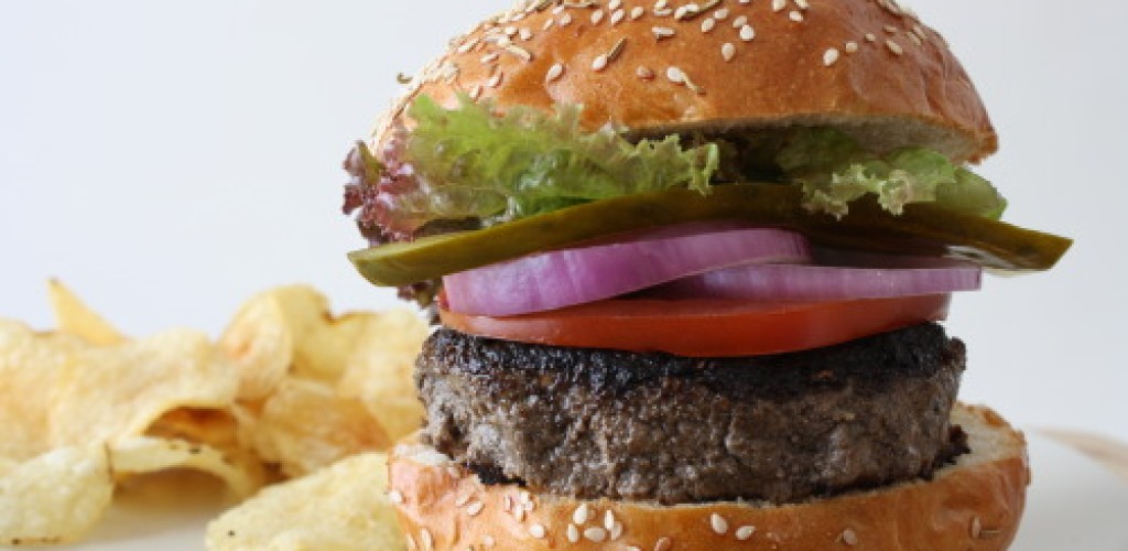 A burger with potato ships on a plate