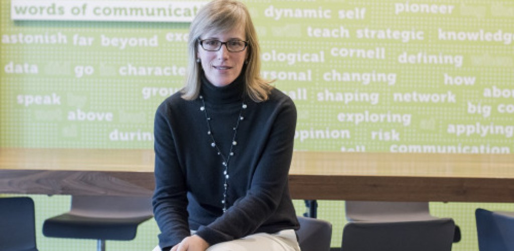 A woman sits on a chair in the Cornell department of communication