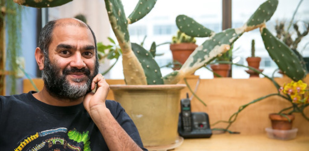A man sits next to plants on a desk