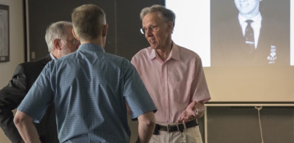 Three men standing together and speaking
