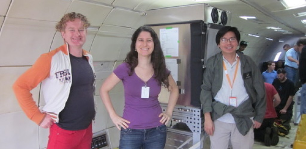Three people stand inside a space simulator
