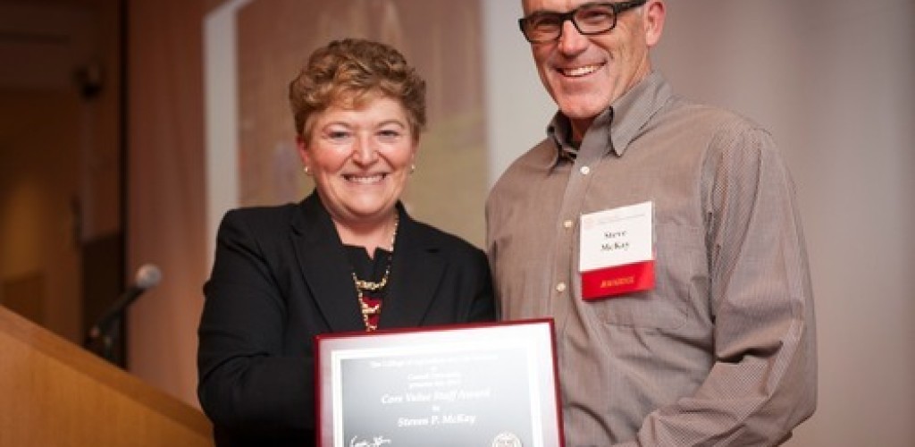 A woman and man stand together holding an award