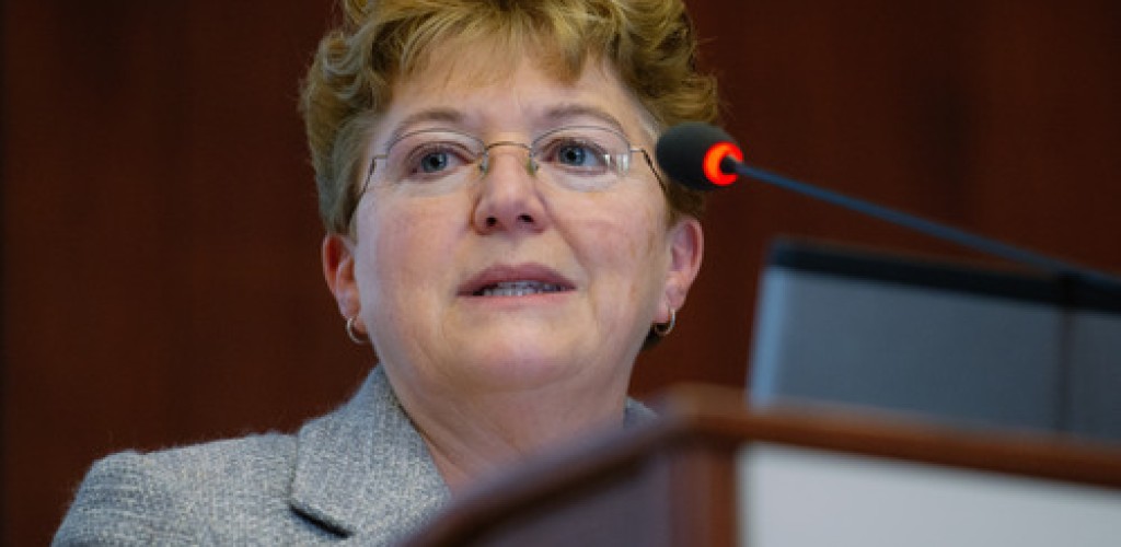 A woman stands at a podium and speaks