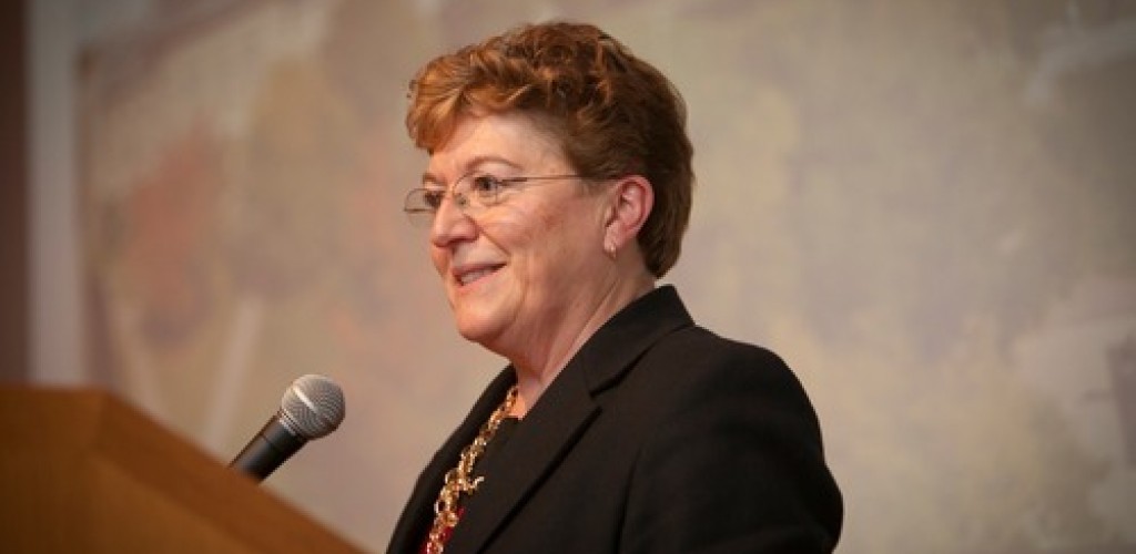 A woman stands at a podium and speaks