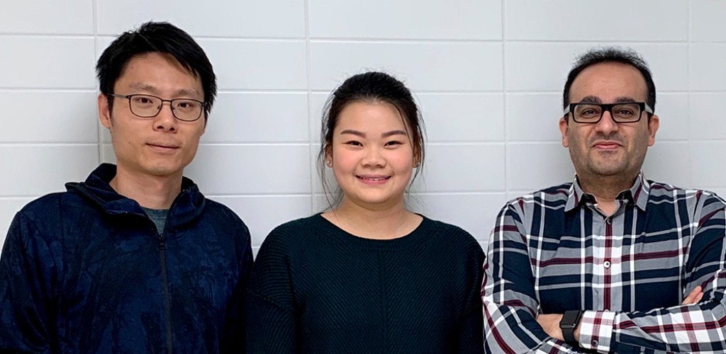 Two men stand on either sides of a women